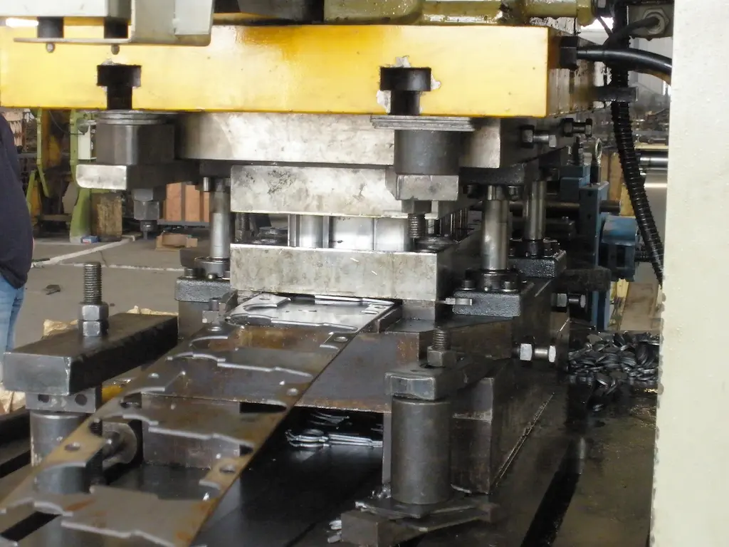 Progressieve stanslijn verwerkt metaalstrip tot onderdelen bij TOS